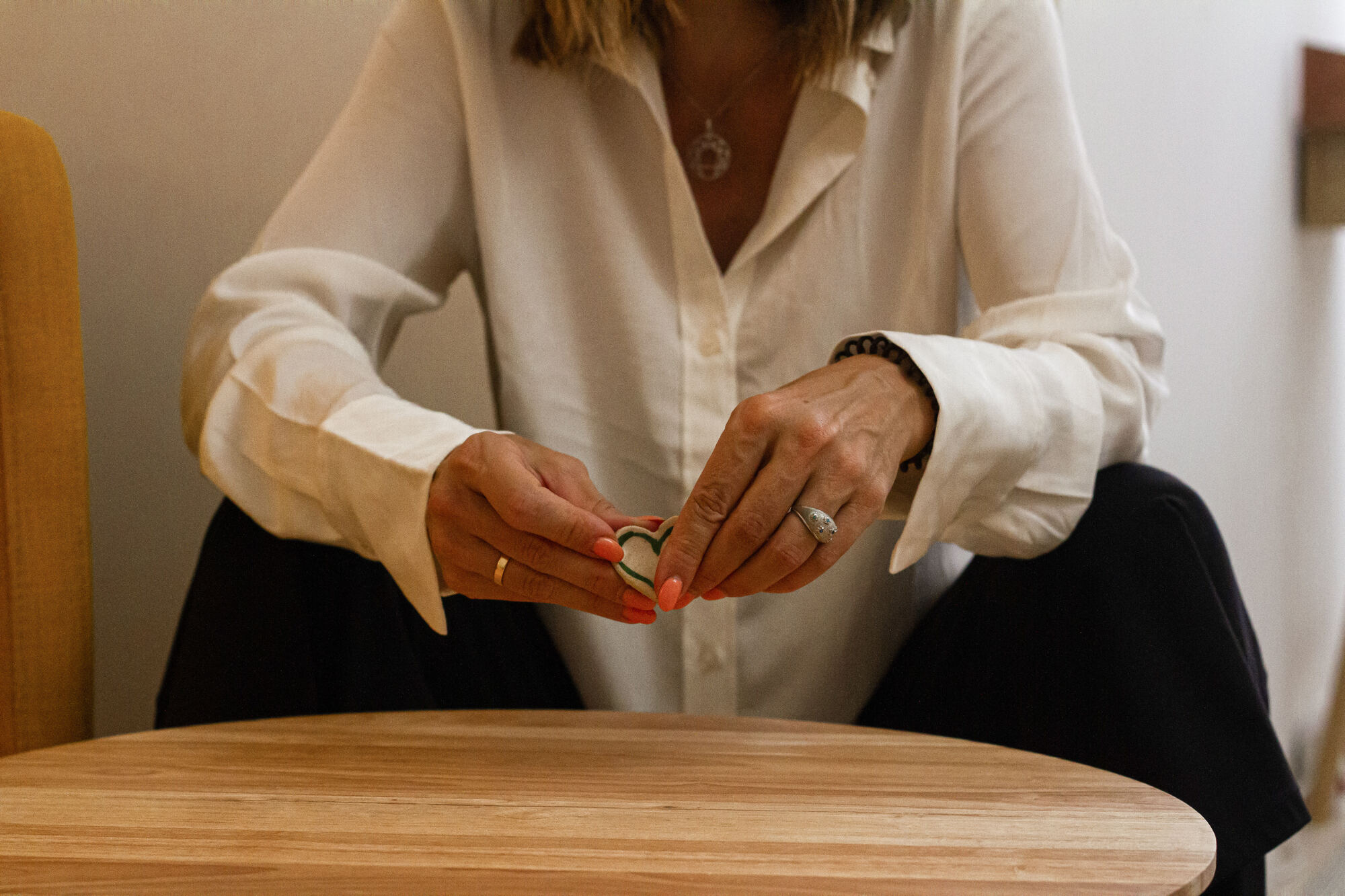 Manos sosteniendo un anillo sobre una mesa de madera clara, en un gesto cercano y cuidadoso.
