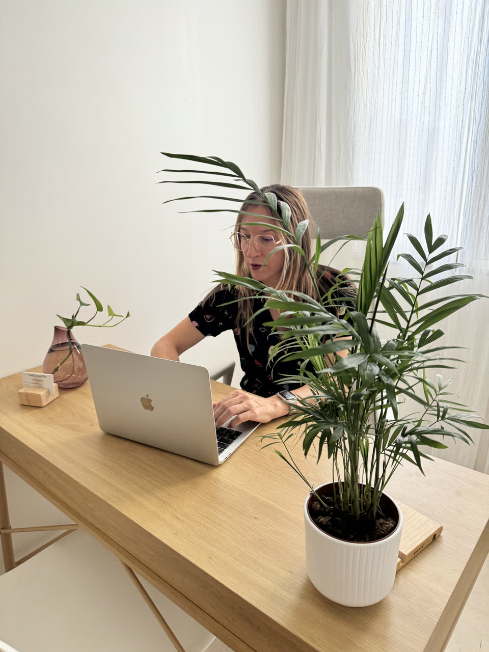 Marta Martín trabajando en su consulta de psicología, junto a la ventana y una planta.